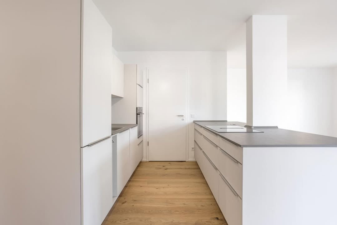 Minimalistische Küche mit Kochinsel, hellen Fronten und klarer Linienführung, umgesetzt vom Küchenstudio Lorinser