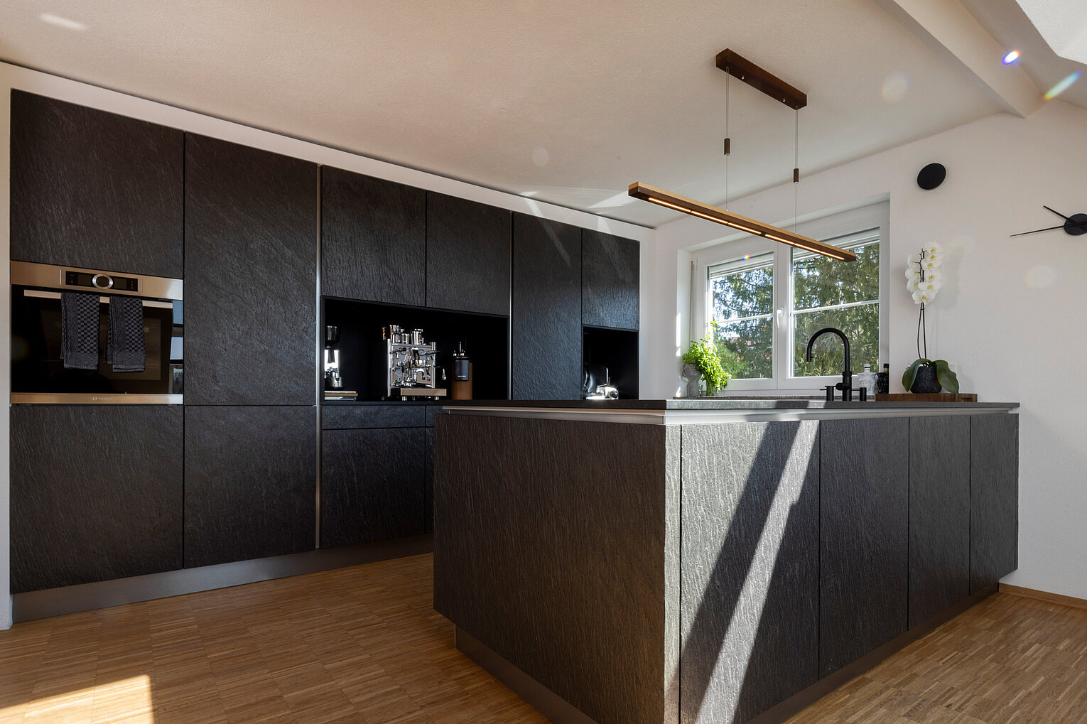 Moderne Küche mit Kochinsel, dunklen Fronten und klarer Linienführung, umgesetzt vom Küchenstudio Lorinser