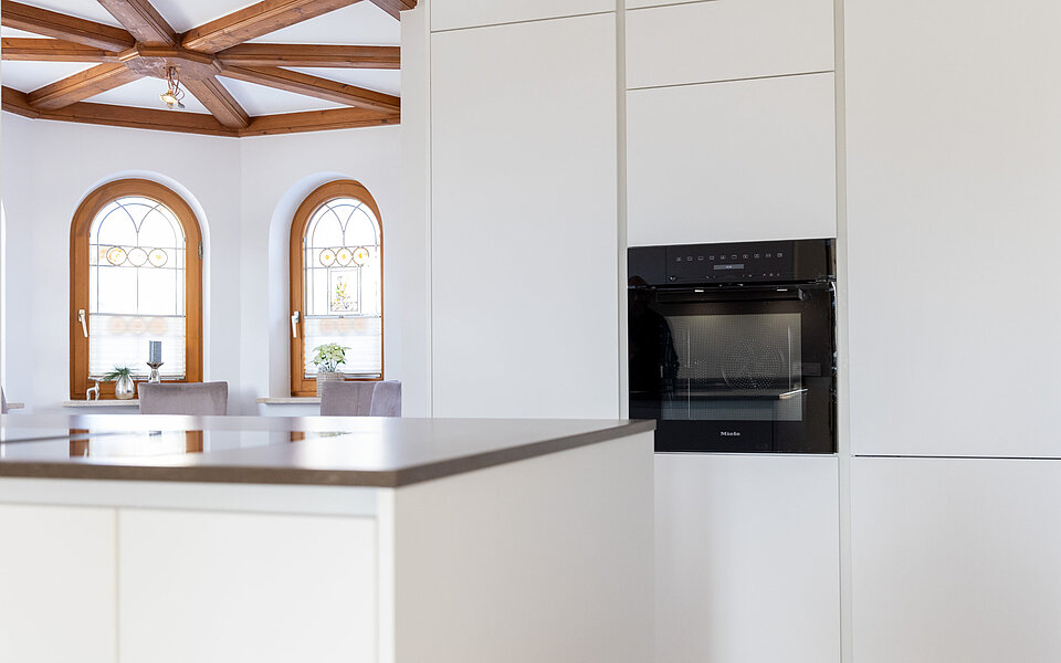 Moderne Küche mit integriertem Backofen und Holzdecke als Designelement, umgesetzt vom Küchenstudio Lorinser