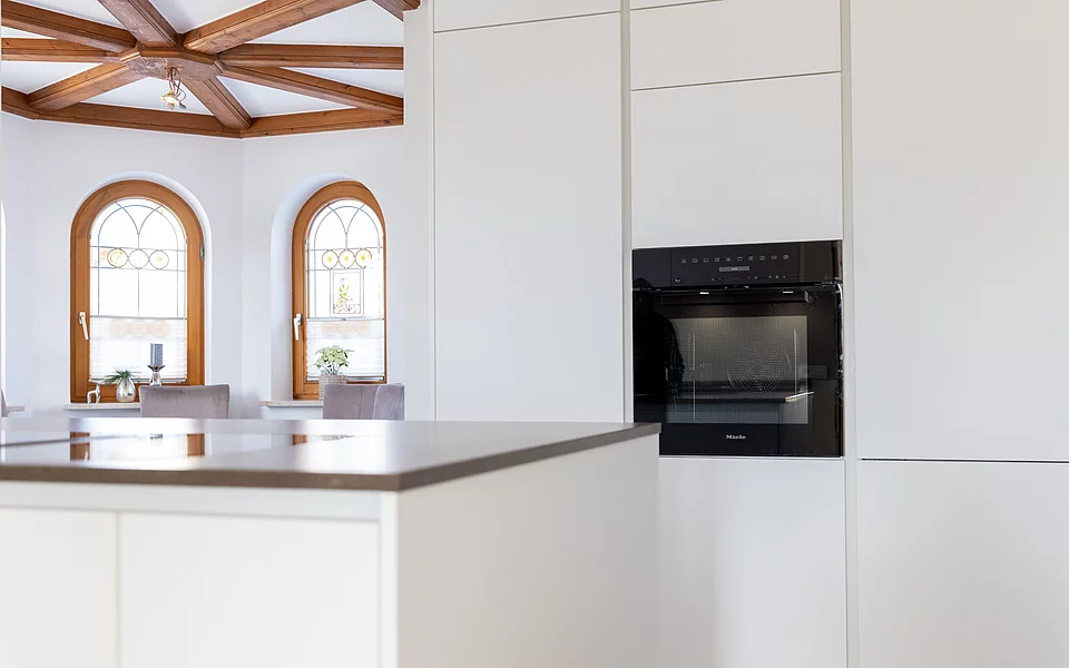 Moderne Küche mit integriertem Backofen und Holzdecke als Designelement, umgesetzt vom Küchenstudio Lorinser