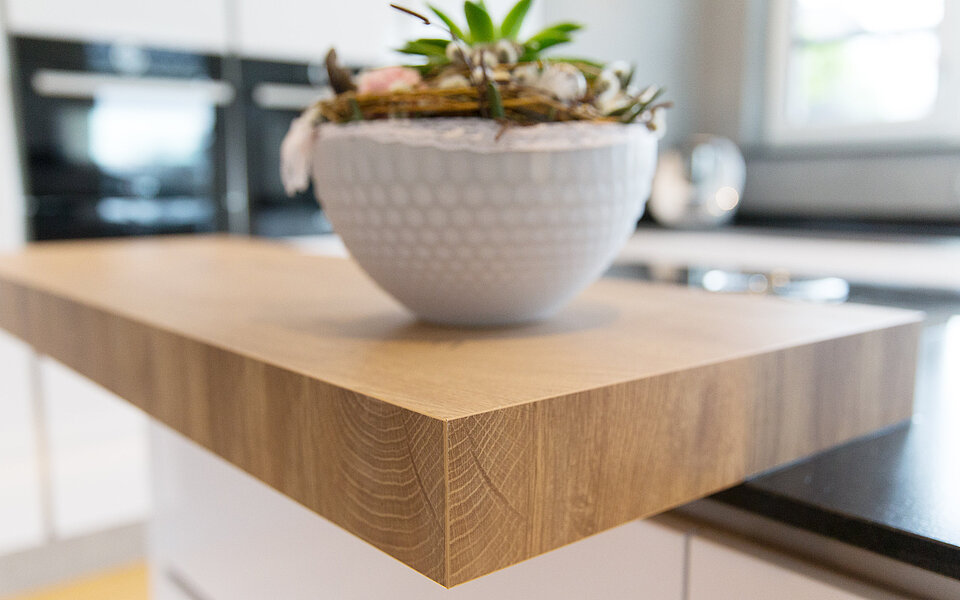 Detailaufnahme einer Küche mit massiver Holzarbeitsplatte und natürlichen Materialien, geplant vom Küchenstudio Lorinser