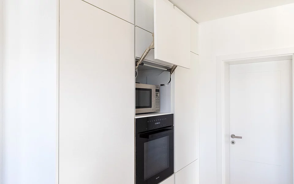 Schlichte Küche mit integrierten Elektrogeräten und klarer Linienführung, geplant vom Küchenstudio Lorinser