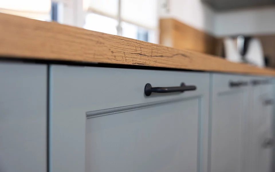 Küche mit grauen Fronten und Holzarbeitsplatte, kombiniert mit modernen Elementen, realisiert vom Küchenstudio Lorinser