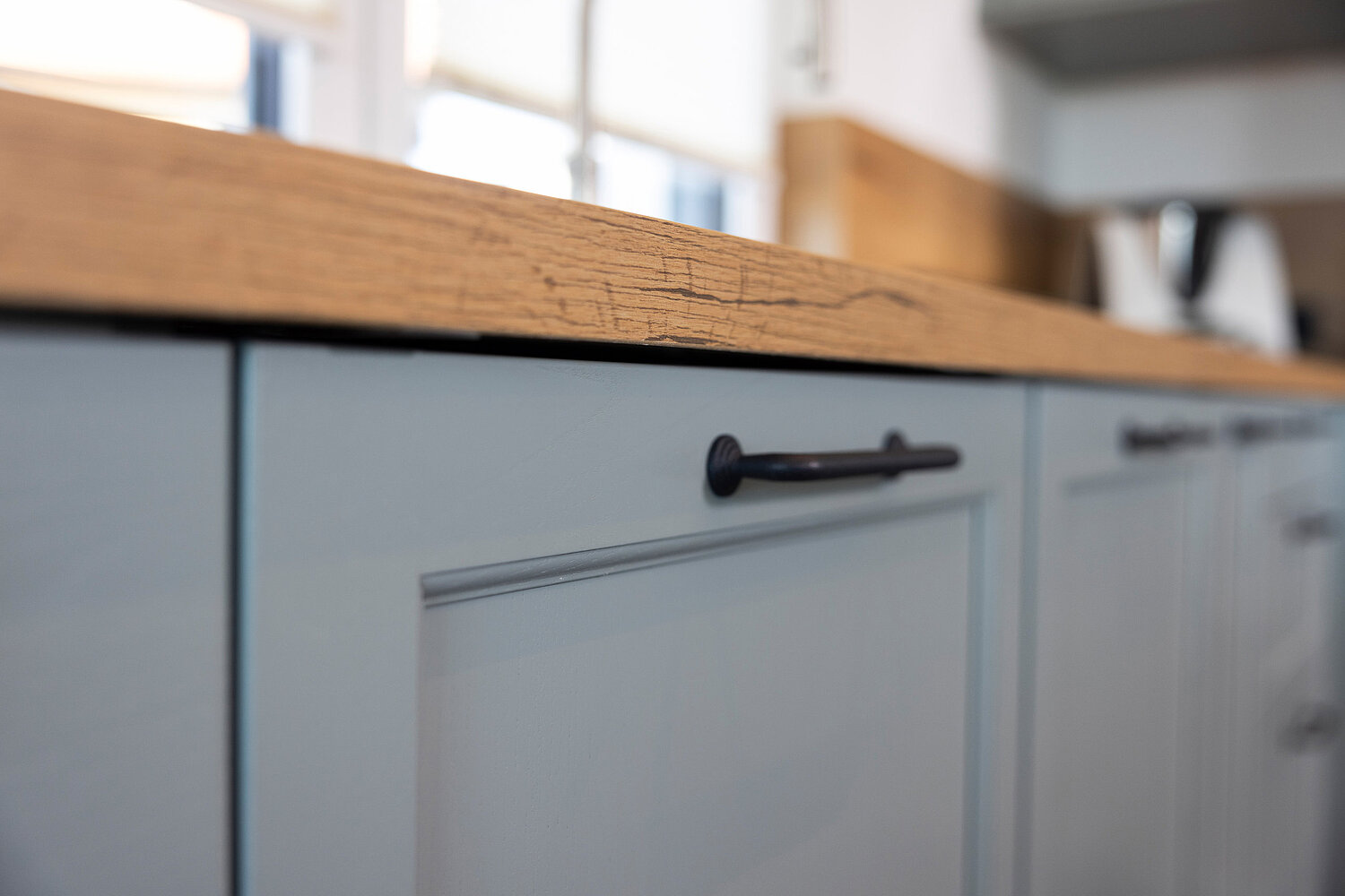 Küche mit grauen Fronten und Holzarbeitsplatte, kombiniert mit modernen Elementen, realisiert vom Küchenstudio Lorinser