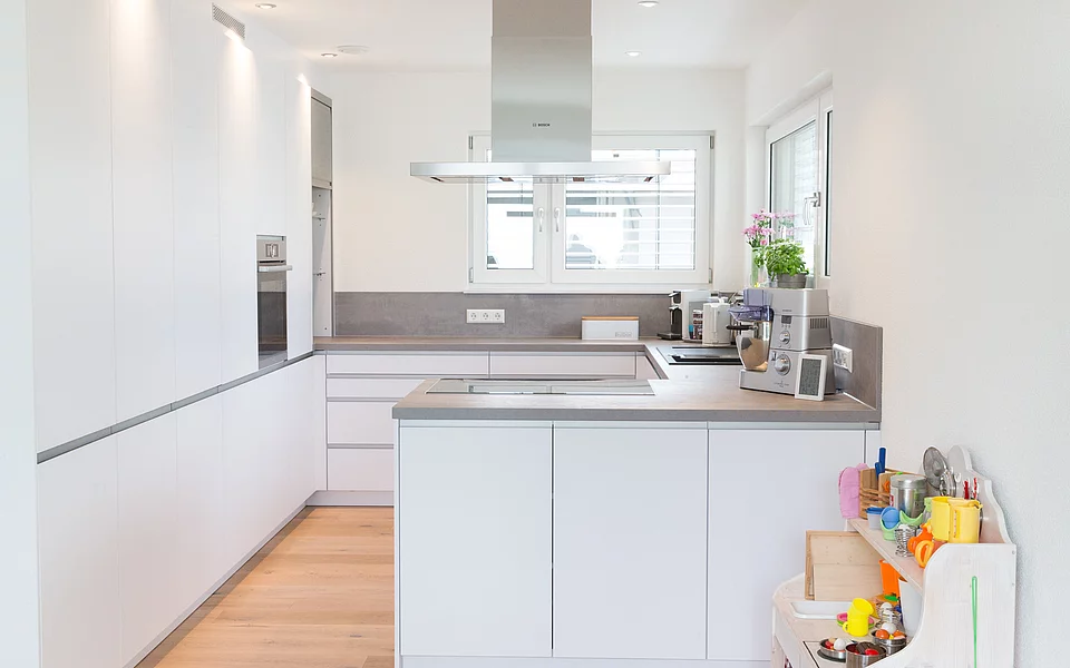 Helle Küche mit großzügiger Arbeitsfläche und Fenster für viel Tageslicht, umgesetzt vom Küchenstudio Lorinser