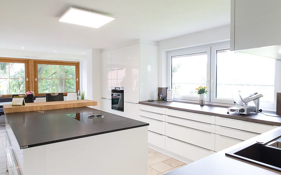 Küche mit zentraler Kochinsel, weißen Fronten und klarer Linienführung, umgesetzt vom Küchenstudio Lorinser