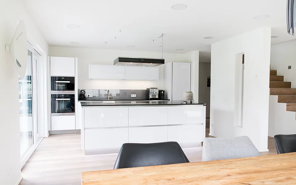 Minimalistische Küche mit weißen Fronten und strukturierter Aufteilung, umgesetzt vom Küchenstudio Lorinser