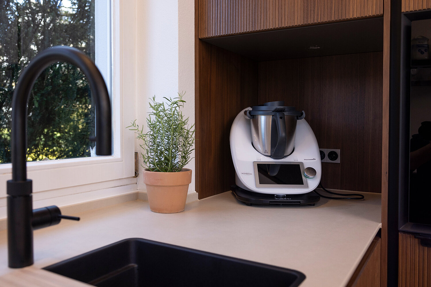 Offene Küche mit großen Fenstern und Blick ins Grüne, geplant und umgesetzt vom Küchenstudio Lorinser