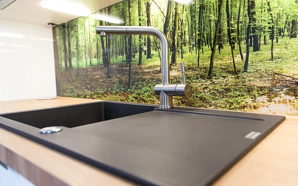 Helle Küche mit Kochinsel und warmen Holzelementen, realisiert vom Küchenstudio Lorinser