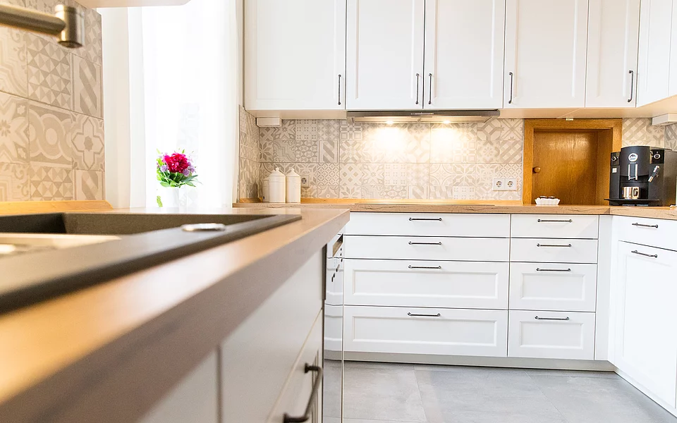 Großzügige U-Küche mit weißen Fronten und warmen Holzelementen, geplant vom Küchenstudio Lorinser