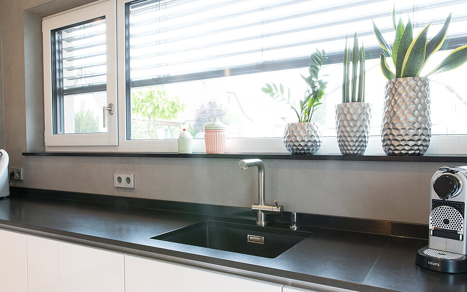 Elegante Küche mit dunklen Fronten und moderner Spüle, realisiert vom Küchenstudio Lorinser