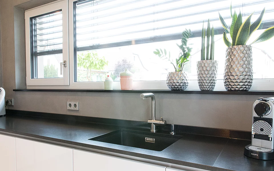 Elegante Küche mit dunklen Fronten und moderner Spüle, realisiert vom Küchenstudio Lorinser