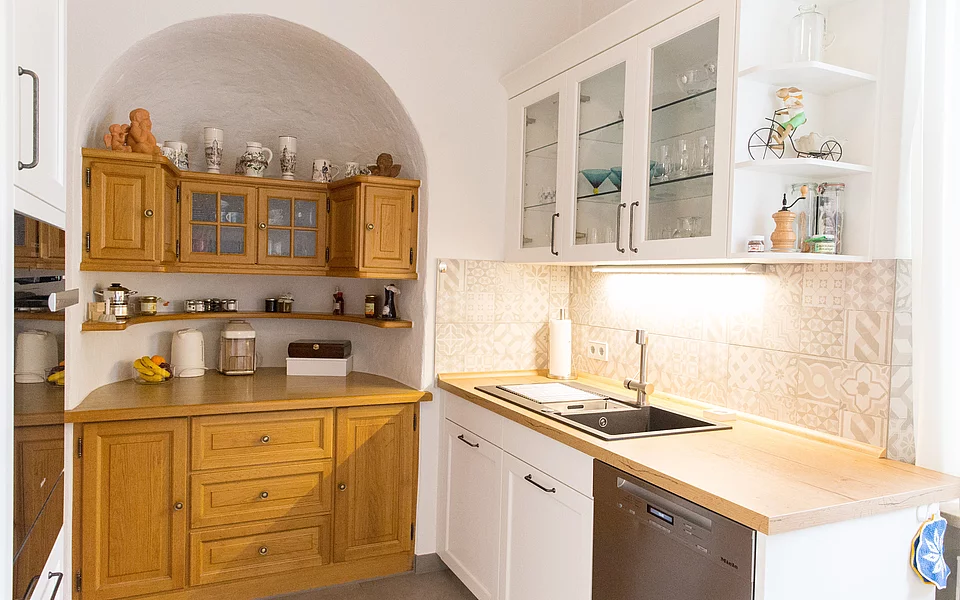 Großzügige Wohnküche mit hellen Fronten, Holzdetails und viel Tageslicht, umgesetzt vom Küchenstudio Lorinser