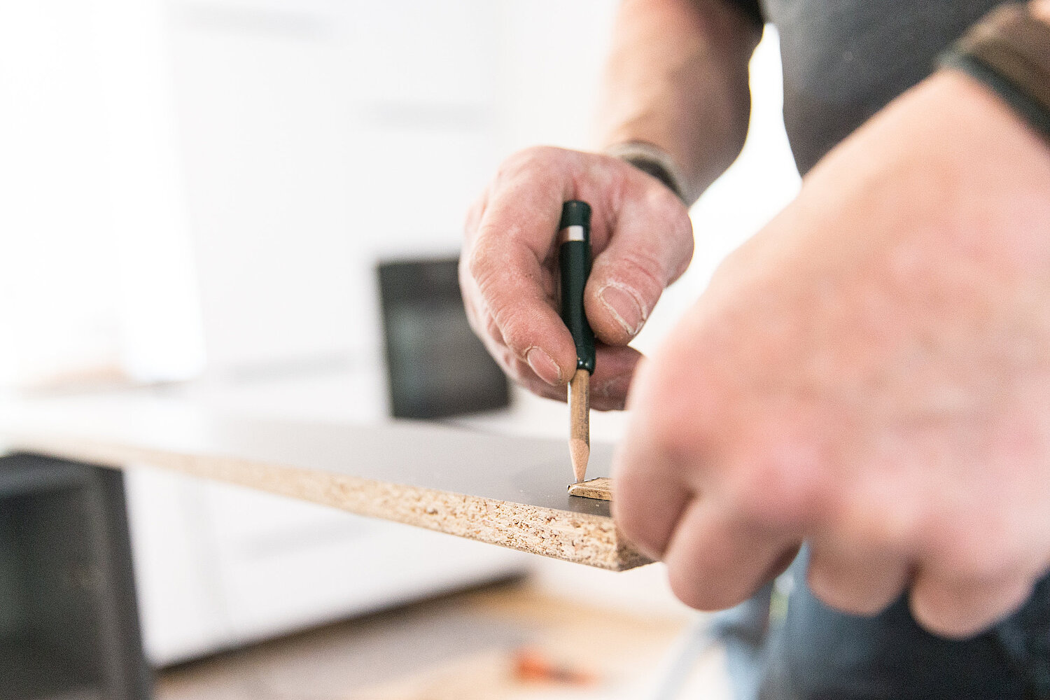 Hände montieren Küchenelement präzise mit Werkzeug, Umsetzung durch Küchenstudio Lorinser