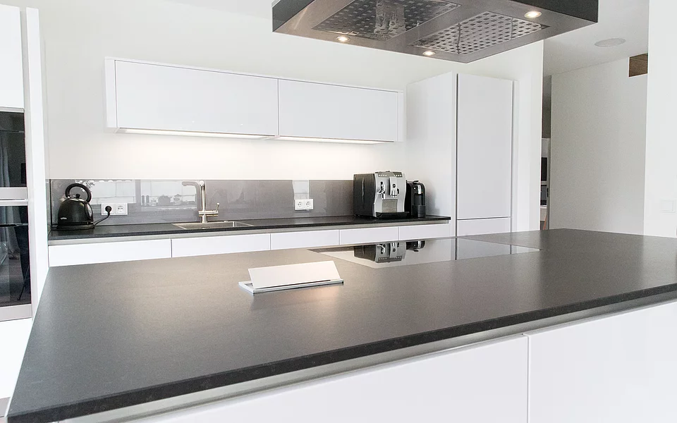 Moderne Küche mit spiegelnder Rückwand und eleganter Linienführung, realisiert vom Küchenstudio Lorinser