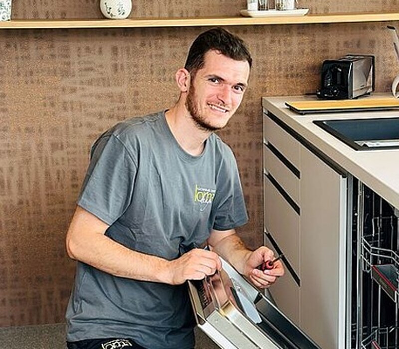 Mann arbeitet an moderner Küche und plant Einrichtung, Beratung durch Küchenstudio Lorinser