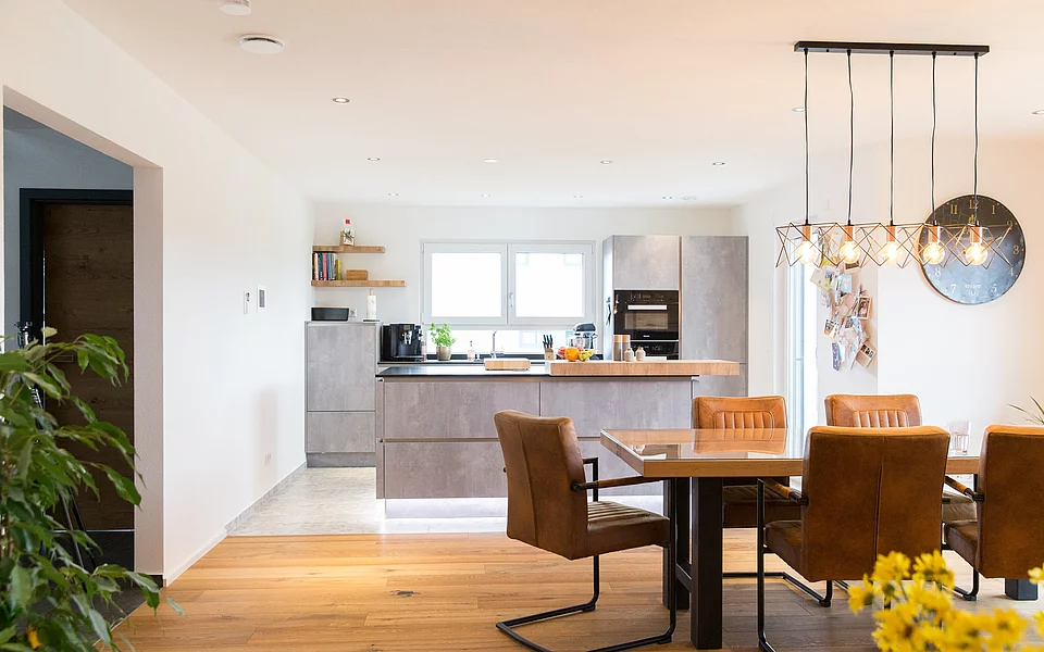 Moderne Wohnküche mit großen Fenstern und Blick ins Grüne, geplant vom Küchenstudio Lorinser