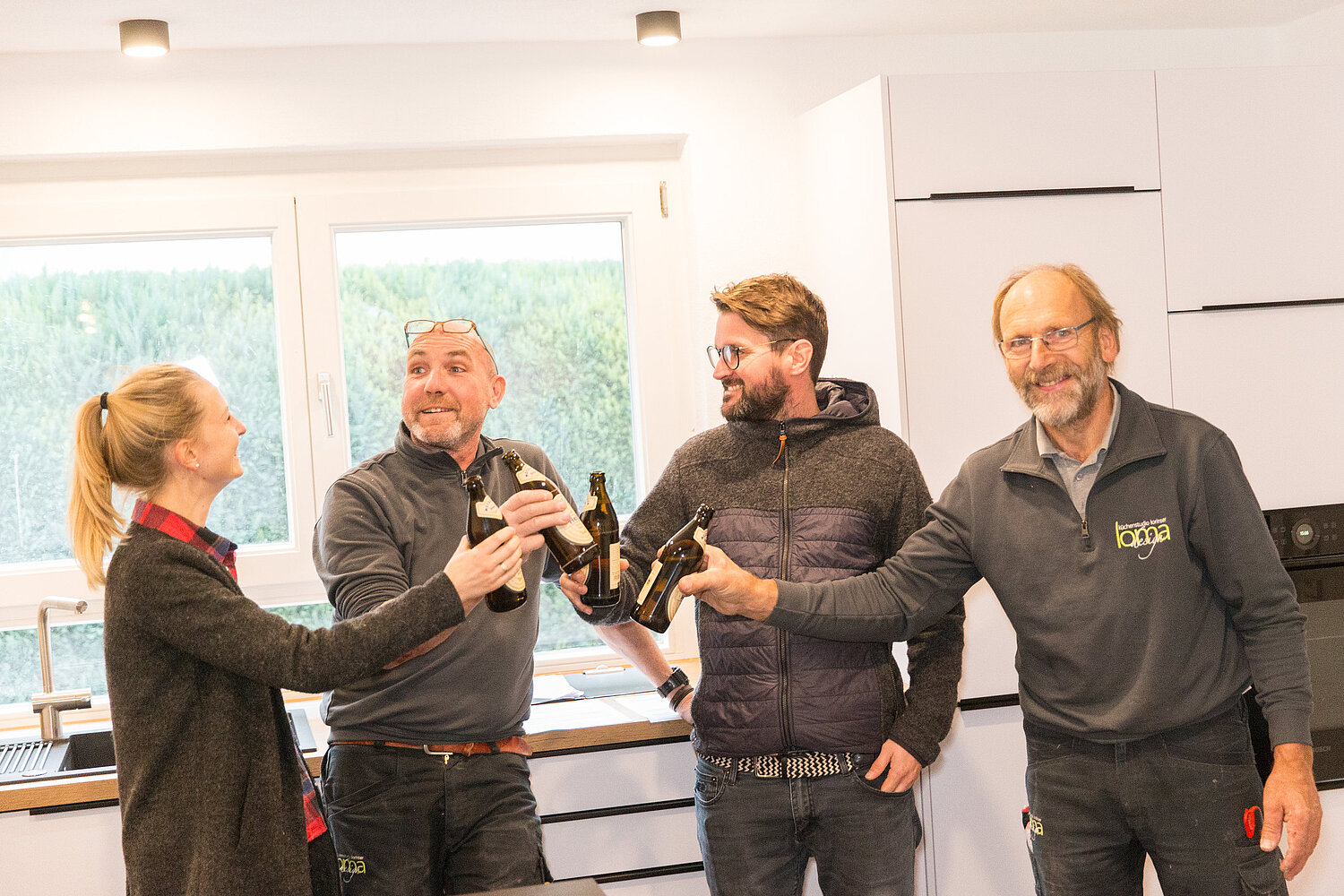 Team von Handwerkern und Kunden steht gemeinsam vor Küche, Mitarbeiter vom Küchenstudio Lorinser