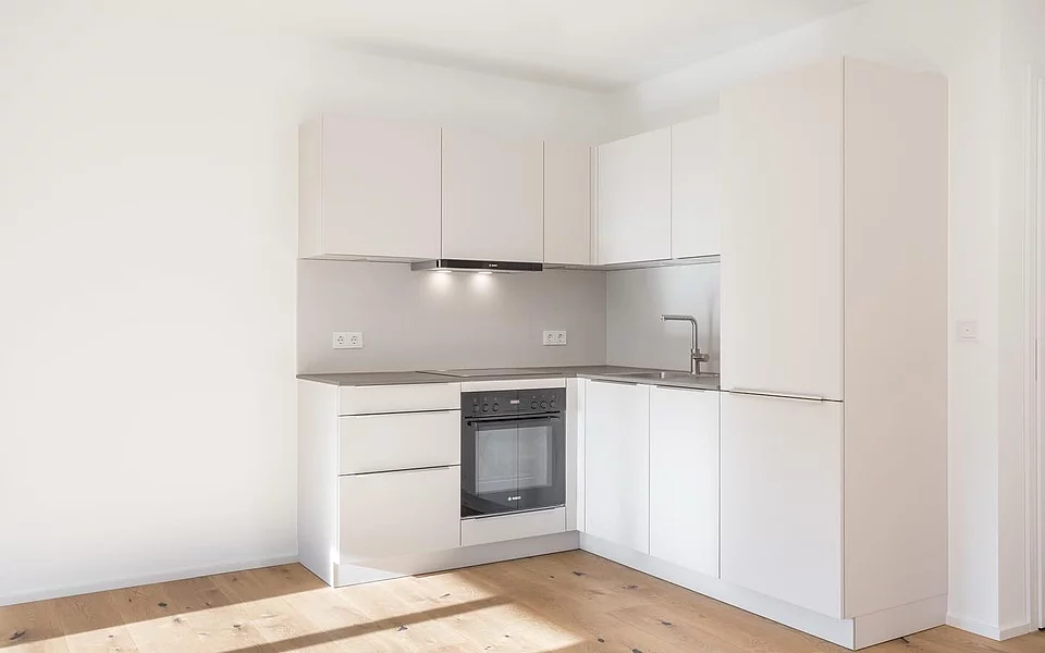 Helle Projektküche mit integriertem Herd und funktionaler Aufteilung, realisiert vom Küchenstudio Lorinser