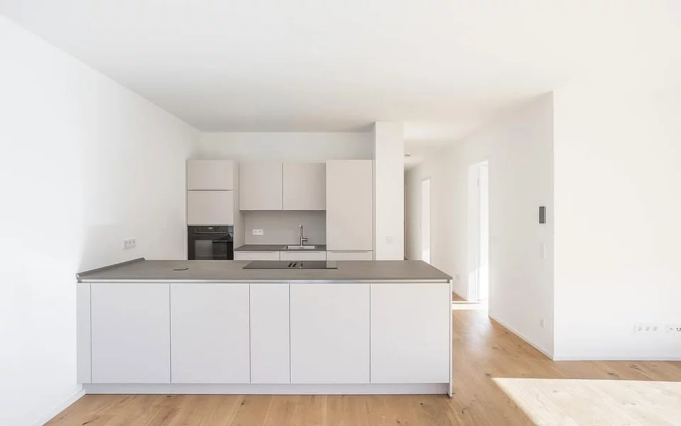 Minimalistische weiße Küche mit klaren Fronten und funktionalem Design, realisiert vom Küchenstudio Lorinser