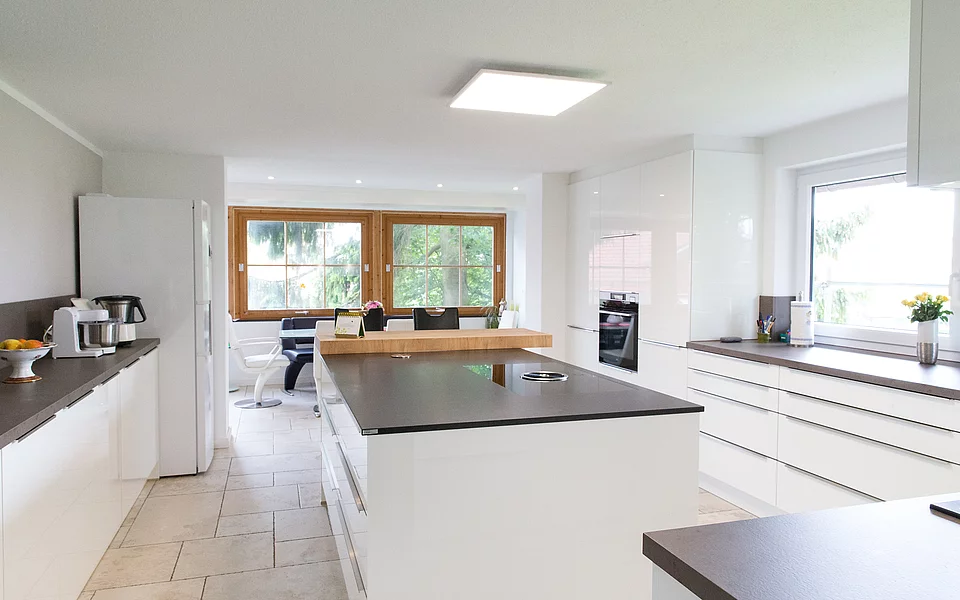 Helle Wohnküche mit offenen Flächen, weißen Fronten und gemütlichem Wohnbereich, umgesetzt vom Küchenstudio Lorinser