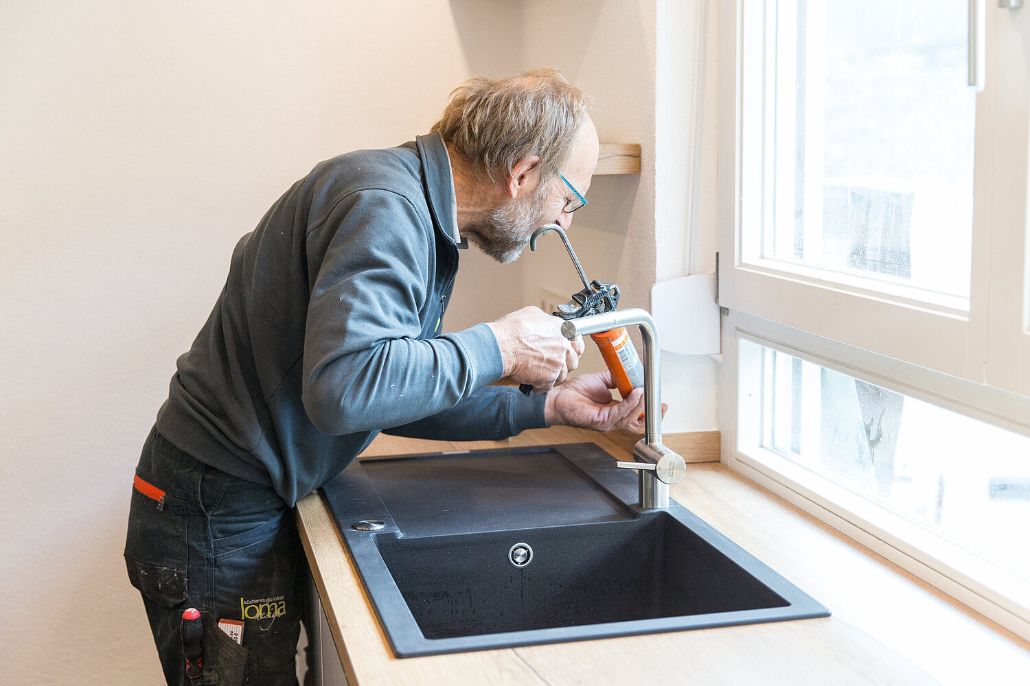 Techniker installiert Küchengerät in moderner Küche, umgesetzt vom Küchenstudio Lorinser