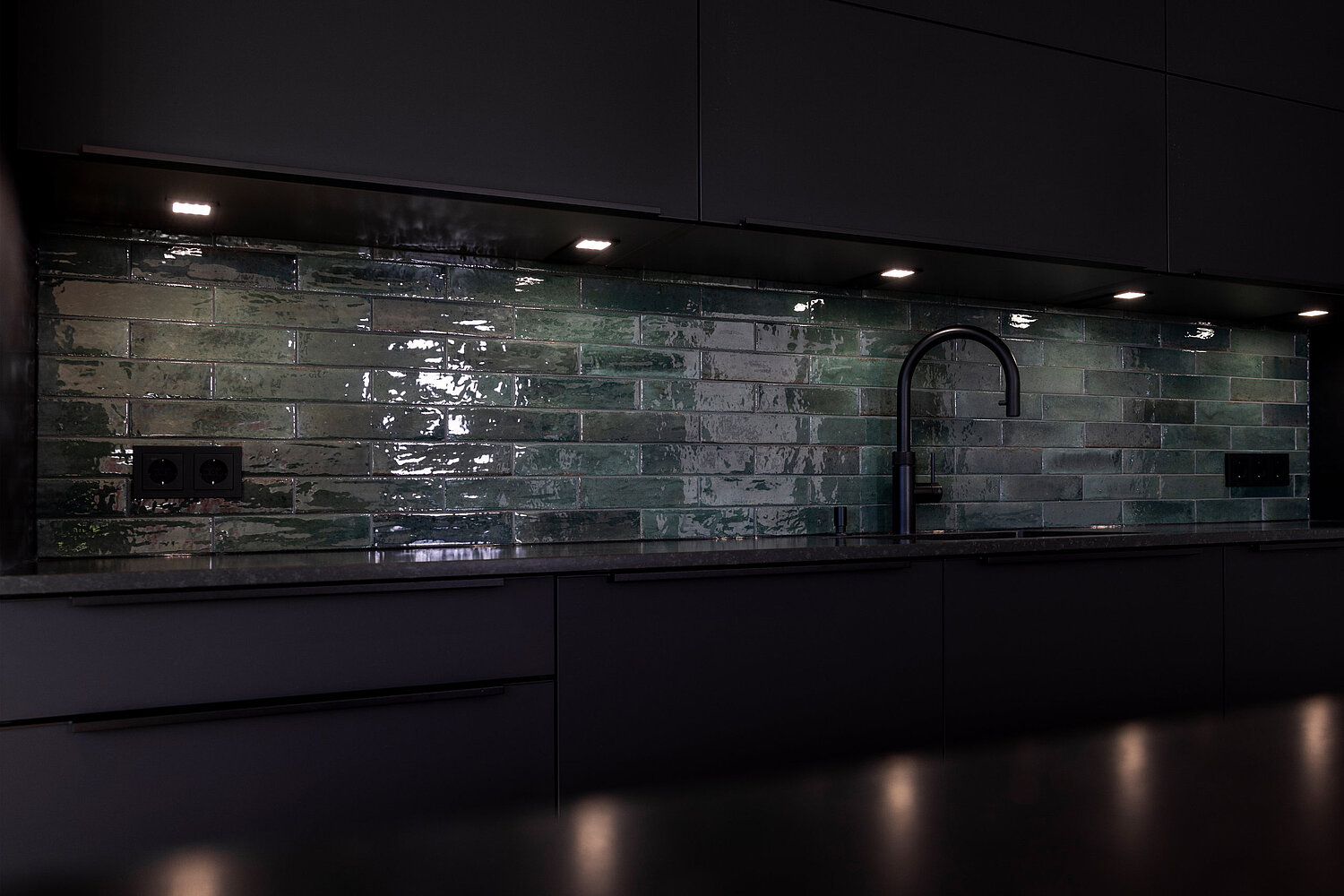 Moderne Küche mit dunklen Fronten und indirekter Beleuchtung für stimmungsvolles Ambiente, realisiert vom Küchenstudio Lorinser