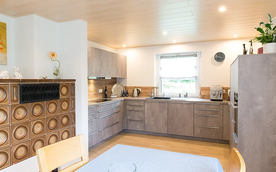 Gemütliche Küche im Landhausstil mit Holzdetails und warmen Farbtönen, umgesetzt vom Küchenstudio Lorinser