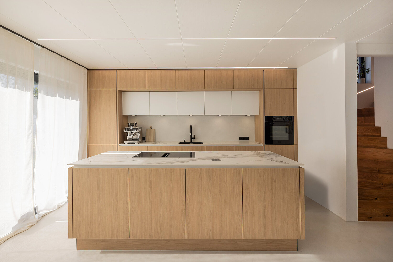 Helle Einbauküche mit Holzfronten, Kücheninsel und offenen Regalen vom Küchenstudio Lorinser