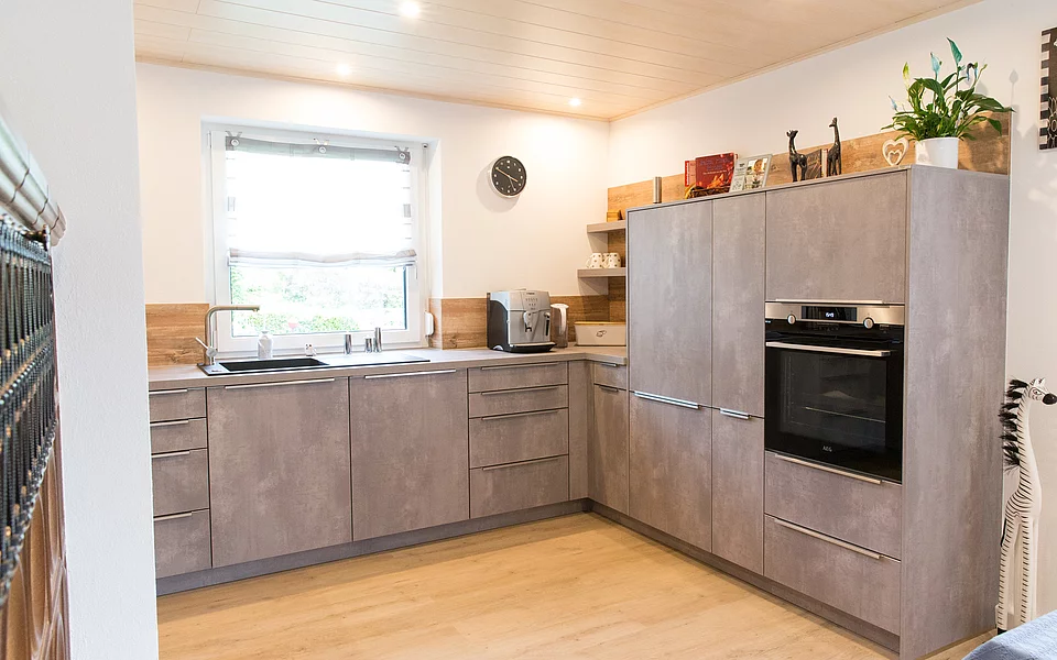 Küche mit Kücheninsel, Holzoptik und klarer Linienführung, geplant vom Küchenstudio Lorinser