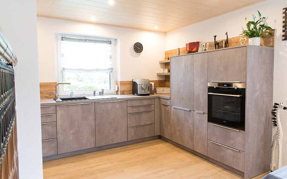 Küche mit Kücheninsel, Holzoptik und klarer Linienführung, geplant vom Küchenstudio Lorinser