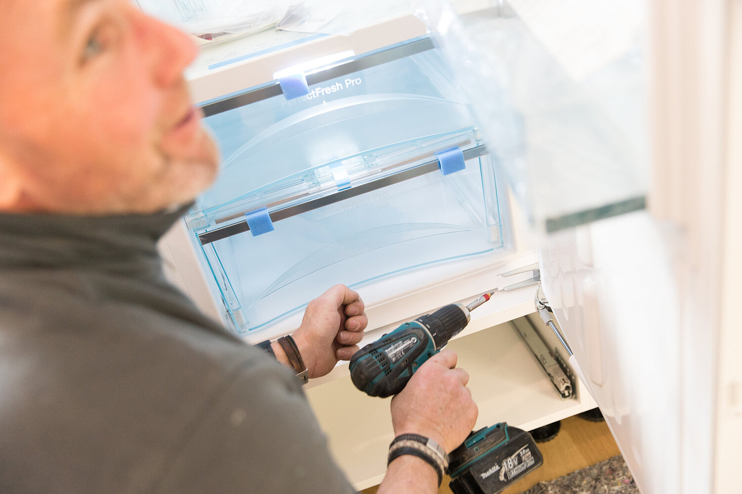 Person betrachtet Küchenpläne und Materialmuster auf einem Tisch, Planung durch Küchenstudio Lorinser