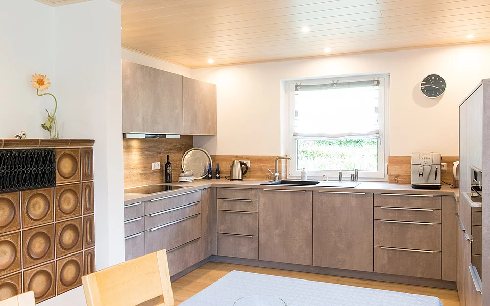 Moderne Wohnküche mit Kamin und Blick ins Grüne, geplant vom Küchenstudio Lorinser