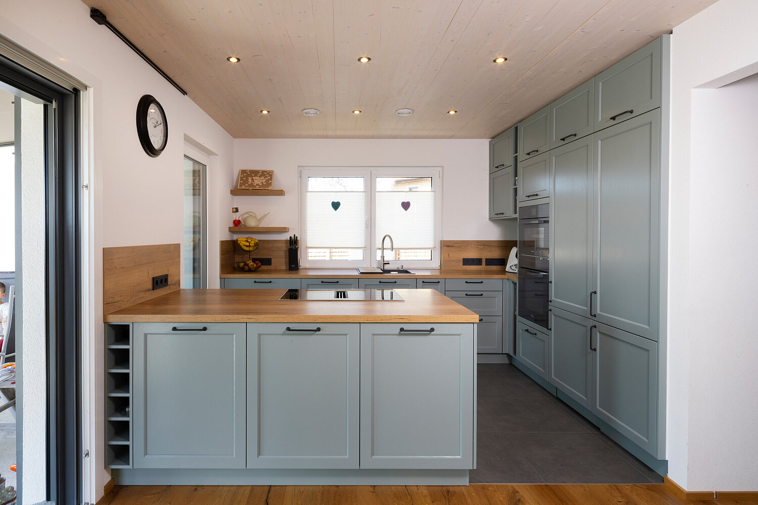 Helle Küche im Landhausstil mit Holzdetails und gemütlicher Atmosphäre, umgesetzt vom Küchenstudio Lorinser