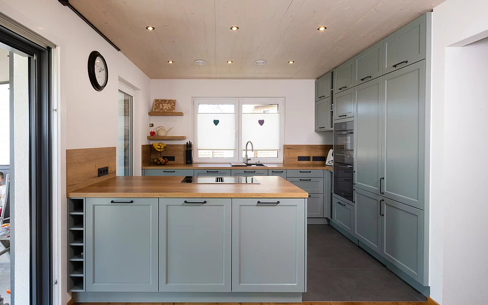 Helle Küche im Landhausstil mit Holzdetails und gemütlicher Atmosphäre, umgesetzt vom Küchenstudio Lorinser