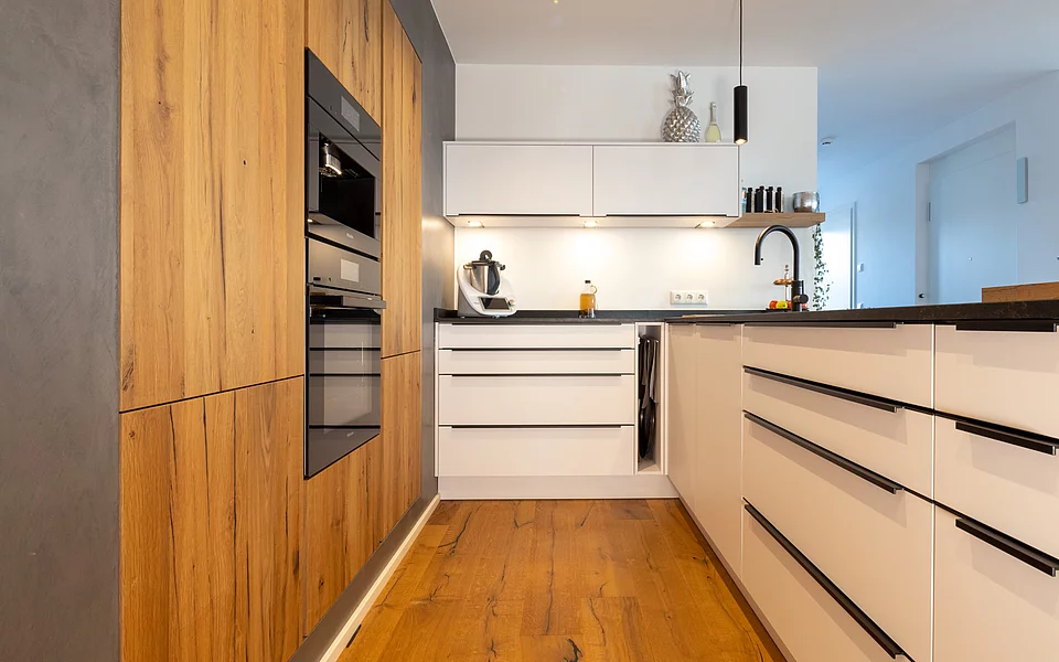 Moderne Küche mit vertikalen Holzfronten und minimalistischer Gestaltung, geplant vom Küchenstudio Lorinser